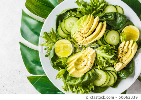 Green avocado and cucumber salad in white plate. 50062339