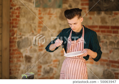 Earthenware in potter's hand. Artist making ornament on ceramic product. Male potter working 50063947