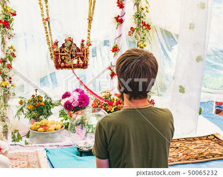 Man gently swing on swing idols of Radha and Krishna statue for begging the blessing on Jhulan Yatra 50065232