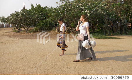two girls, mother and daughter, tourists pass through the territory of a wooden Buddhist temple in two girls, mother and daughter, tourists pass through the territory of a wooden Buddhist temple in 50066779