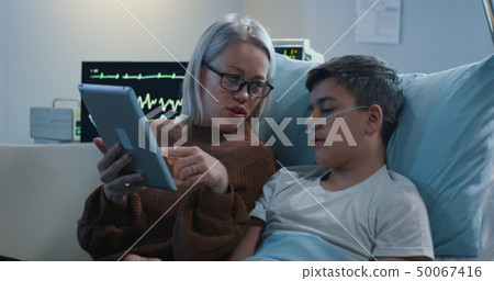 Mother reading aloud to sick son 50067416