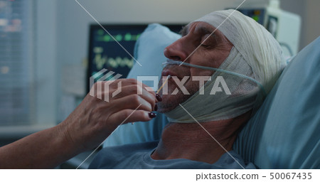 Nurse lubricating patients mouth with cotton swab Nurse lubricating patients mouth with cotton swab 50067435