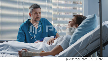 Male doctor visiting teenager patient in hospital 50067658