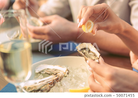Gentle lady carrying piece of lemon and squeezing it on fresh oyster 50071455