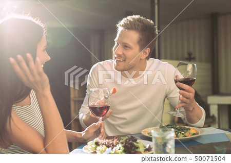 Communicative boyfriend with light stubble eating salad and talking with girl 50071504