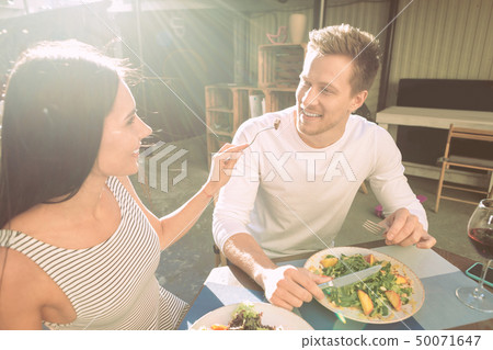 Joyful appealing girl carrying fork with food and proposing to her boyfriend 50071647