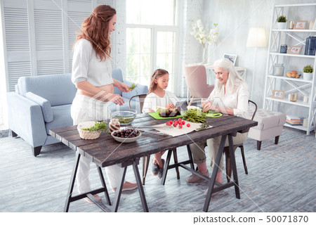 Pregnant woman cooking salad with her mom and older daughter 50071870