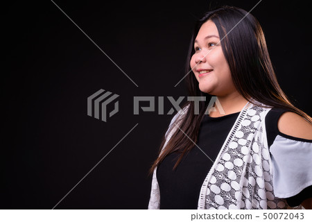 Beautiful overweight Asian woman against black background 50072043