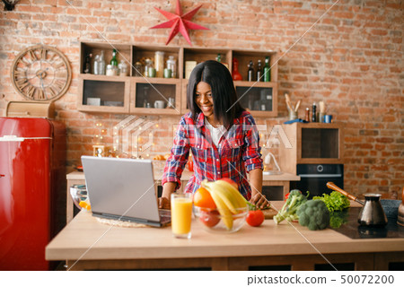 Black woman looking recipe on laptop 50072200
