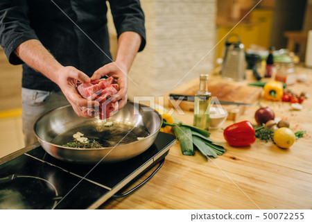 Male person cooking meat with herbs in a pan 50072255