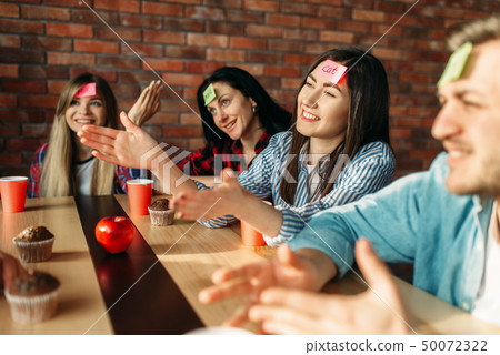 Smiling friends playing sticker notes to forehead Smiling friends playing sticker notes to forehead 50072322