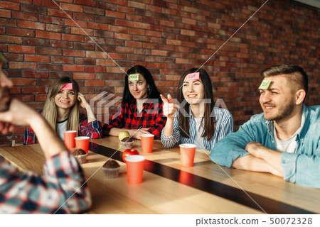 Smiling friends playing sticker notes to forehead  50072328