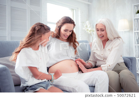Mother and daughter touching pregnant tummy of young woman Mother and daughter touching pregnant tummy of young woman 50072621