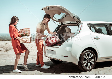 Handsome brunette man taking bag from trunk 50073495