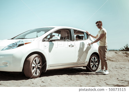 Handsome young man opening door of his auto Handsome young man opening door of his auto 50073515