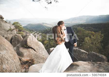 Beautiful wedding couple, bride and groom, in love on the background of mountains Beautiful wedding couple, bride and groom, in love on the background of mountains 50074084