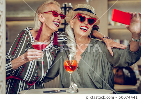 Joyful nice stylish women taking pics together 50074441