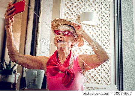 Cheerful nice elderly woman taking great photos 50074663