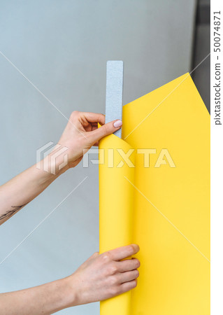 Women's hands wrap a gray nail file in paper 50074871