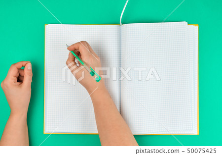 female hand holding pen, near  blank open notebook 50075425