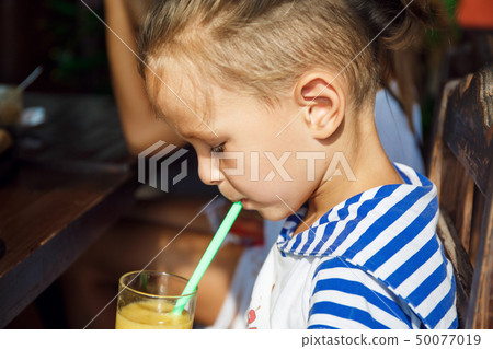 beautiful boy is drinking orange juice  50077019