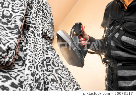 Closeup woman hand smooths the dress with a steam Closeup woman hand smooths the dress with a steam 50078117