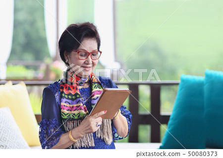 senior woman sitting on the sofa and using tablet senior woman sitting on the sofa and using tablet 50080373