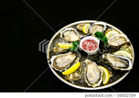 Fresh oysters on a plate with ice and lemon slices 50082589