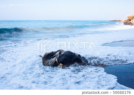 Sandy beach and soft blue ocean wave with white foam. 50088176