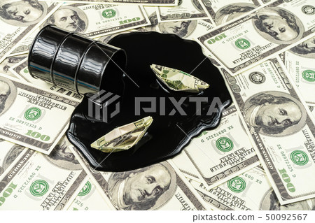 Spilled oil from a barrel to a dollar bill background.Oil barrel price concept 50092567