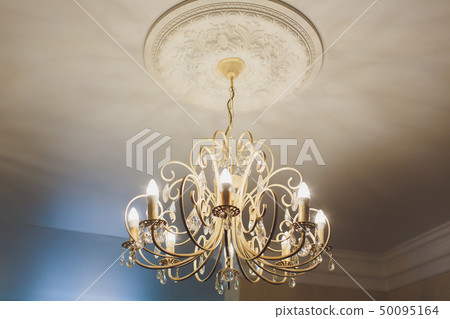 luxury expensive chandelier hanging under ceiling in palace. luxury expensive chandelier hanging under ceiling in palace. 50095164