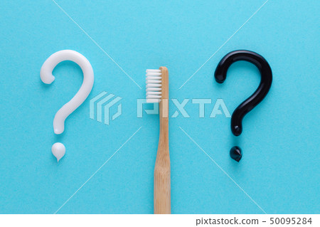question from white and black toothpaste, teeth care concept, wooden toothbrush on blue background 50095284