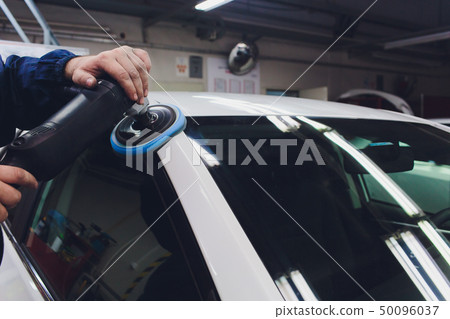 Car detailing - Hands with orbital polisher in auto repair shop. Selective focus. 50096037