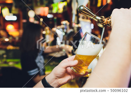 We meet oktoberfest. Hand of bartender pouring a large lager beer in tap. Pouring beer for client 50096102