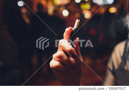 heat-not-burn tobacco product technology. Woman holding e-cigarette in his hand before smoking. heat-not-burn tobacco product technology. Woman holding e-cigarette in his hand before smoking. 50097017