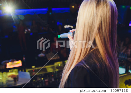 The female student is holding the black wireless microphone in the left hand and do the public The female student is holding the black wireless microphone in the left hand and do the public 50097118