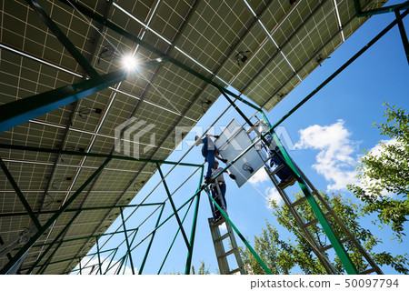 Three mounters holding solar panels on high metallic construction. Three mounters holding solar panels on high metallic construction. 50097794