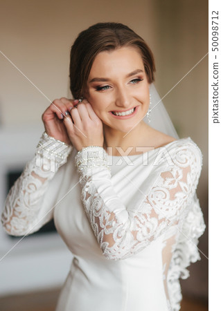 Elegant bride wear earrings. Charming woman in beautiful wedding dress Elegant bride wear earrings. Charming woman in beautiful wedding dress 50098712