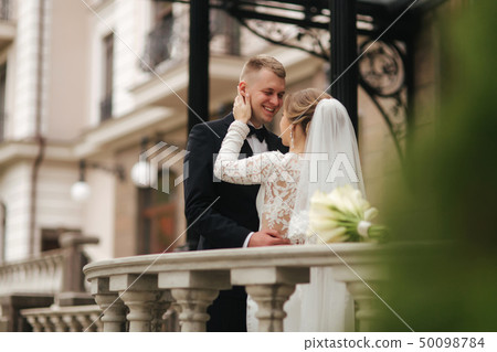 Beautiful wedding couple stand on the balcony. Stylish bride and groom in autumn weather outside 50098784