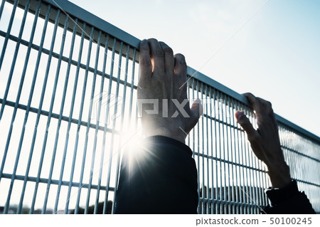 man climbing up a metal fence man climbing up a metal fence 50100245