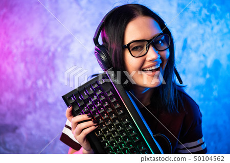 Gamer girl playing with computer at home. Young female posing with computer keyboard. Gamer girl playing with computer at home. Young female posing with computer keyboard. 50104562