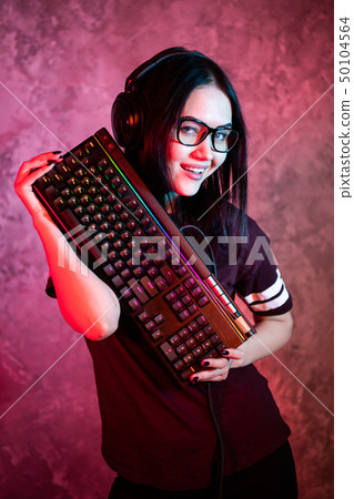 Gamer girl playing with computer at home. Young female posing with computer keyboard. Gamer girl playing with computer at home. Young female posing with computer keyboard. 50104564