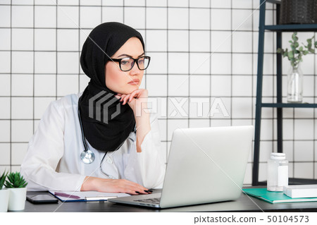 Middle age senior arab nurse woman wearing hijab at medical office with hand on chin thinking about Middle age senior arab nurse woman wearing hijab at medical office with hand on chin thinking about 50104573