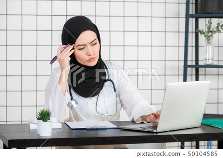 Middle age senior arab nurse woman wearing hijab at medical office with hand on chin thinking about Middle age senior arab nurse woman wearing hijab at medical office with hand on chin thinking about 50104585