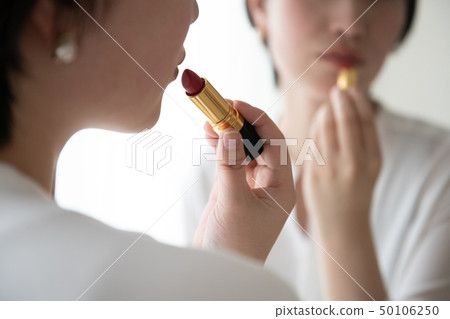 應用唇膏的年輕日本婦女構成秀麗 應用唇膏的年輕日本婦女構成秀麗 50106250