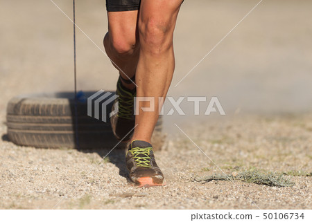 Mud race runners, athlete pulling car tires 50106734