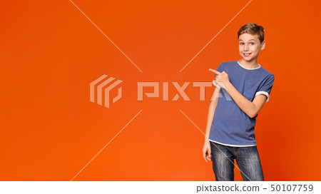 Cute little boy pointing away on orange background Cute little boy pointing away on orange background 50107759