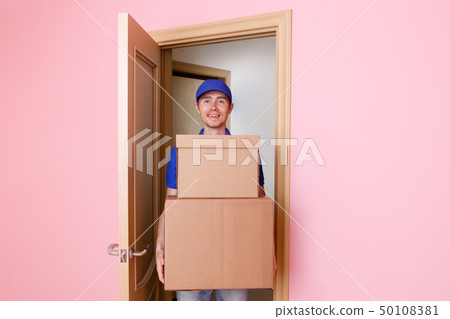 Image of courier man in blue t-shirt and baseball cap with cardboard boxes in hands. 50108381