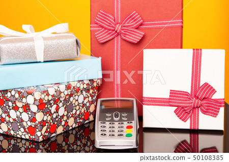Terminal, boxes with gifts on black glass table and yellow background. 50108385