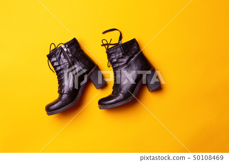 Elegant women black heeled boots. Top view of black boots on a yellow background. 50108469